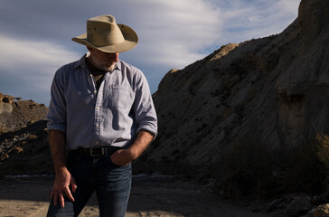 Adult man in cowboy hat standing against mountains in Tabernas desert. Almeria, Spain