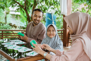 Father, mother and daughter making paper decorations preparing to decorate