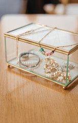 Glass box with gold decor and decorations. Beautiful chains and bracelets. Stylish box
