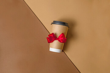 Brown paper cup with red flat lei bow. Gift coffee to go with a beautiful ribbon. Festive...