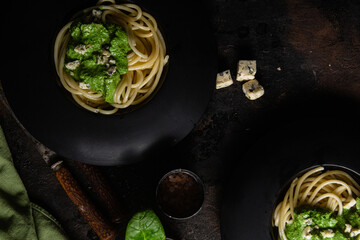 Pasta with spinach sauce on a black plate