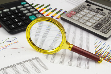 Business concept with magnifying glass, calculators and financial documents	