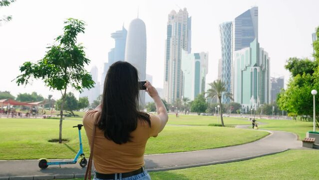Woman tourist with skyline of Doha seen from Al Dafna Park. Mordern skyscrapers and towers on background
