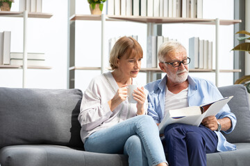 senior couple reading a book and self learning in living room