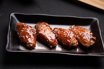 Fried chicken wings with spicy and sweet Korean sauce topped with white sesame seeds