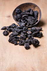 sun dried garcinia fruits scattered on a wooden table top, black shriveled flavoring herb native to south asia, also known as brindle berry, goraka or malabar tamarind, taken in shallow depth of field - obrazy, fototapety, plakaty