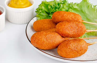 American fast food. Corn dogs on white background with mustard. Junk food and unhealthy eating concept