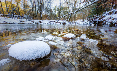 snow covered stones in river in winter