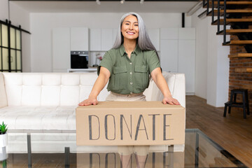 Smiling gray-haired woman encourages to share things with those in need, middle-aged Asian lady...