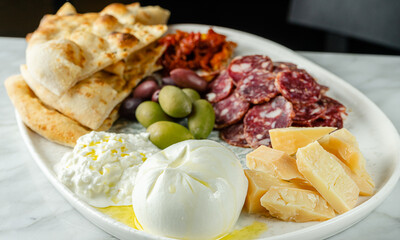 Italian snacks or antipasto platter with different cheese, meat and focaccia. Selective focus.