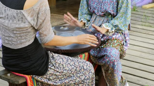 Two girls play tank drum, percussion musical instrument