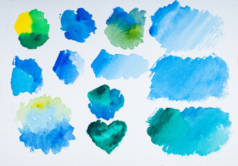 Watercolor palette of blues and greens on white textured paper.