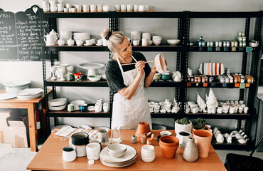 Adding a final and personal touch. Cropped shot of an attractive mature woman standing alone and painting a pottery bowl in her workshop.