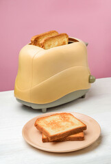 A plate of toast and a toaster are on the table.