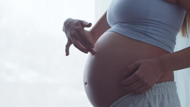 Young pregnant woman is resting at home and expecting a baby. The concept of pregnancy, motherhood, health and lifestyle.