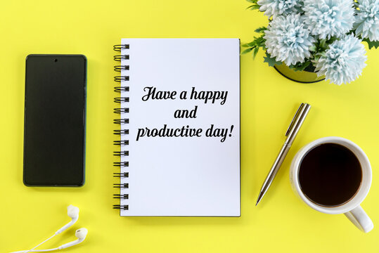 Business motivational words - Have a happy and productive day. With text message write on a book, a cup of morning black coffee, pen, and blue flowers on yellow table top view background.