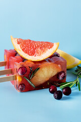 Frozen Refreshing Summer Cocktail Popsicles Recipe Cold Sweet Berry and Citrus Tea with Rosemary Blue Background Vertical