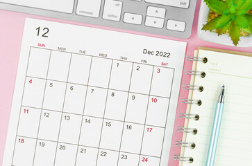 December 2022 calendar sheet with keyboard computer on pink background.