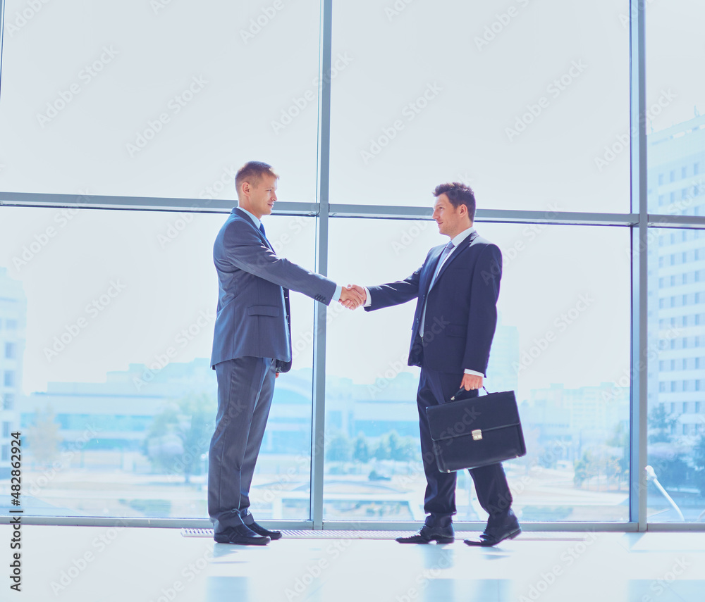 Wall mural Full length image of two successful business men shaking hands with each other