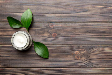 Organic cosmetic products with green leaves on wooden background. Copy space, flat lay