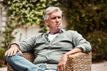 I feel like a king. Cropped shot of a relaxed senior man smoking a marijuana joint on his own inside of his garden at home during the day.