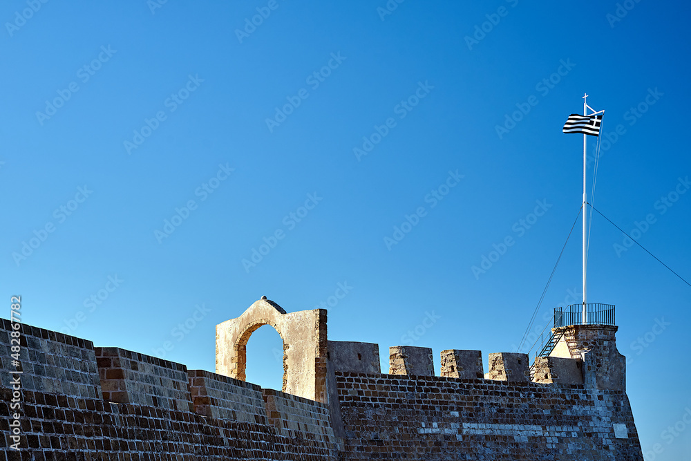 Wall mural A bastion of a Venetian fortress with a Greek flag on a mast in the city of Chania on the island of Crete