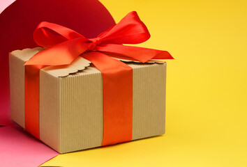 Gift cardboard box with a red bow on a multi-colored background