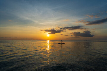 Silhouette of a man on a paddleboard during beautiful sunset on the water of the sea