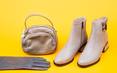 stylish leather beige boots gloves and hat on yellow background, fashion accessories
