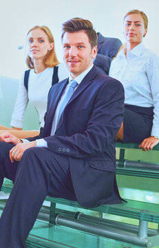 Portrait of young businessman in office with colleagues in the background . Portrait of young businessman.
