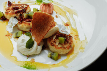 An ideal breakfast. Cottage cheese pancakes with caramel, almonds and cream sauce in a white plate. Ukrainian syrniki