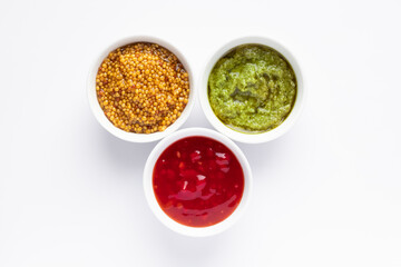 Sauce set - ketchup, pesto and mustard seeds in gravy bowls isolated on white background