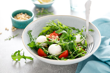 Fresh vegetable Caprese salad with arugula, tomato, pine nuts and mini mozzarella cheese