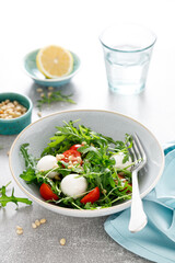 Fresh vegetable Caprese salad with arugula, tomato, pine nuts and mini mozzarella cheese