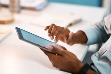 Connecting to the business world. Shot of an unrecognizable businessman using a digital tablet while working late in his office.