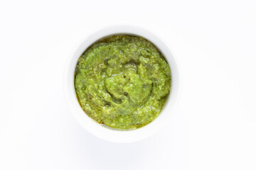 Bowl of green italian homemade sauce pesto isolated on white background.