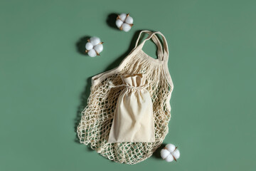 Cotton reusable bag and mesh and cotton buds on green background. Eco shopping.