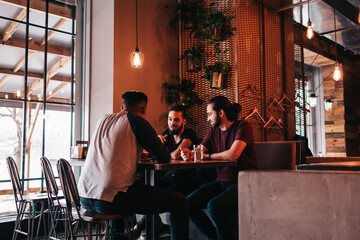 Group of mixed race young men talking in lounge bar. Multiracial friends hanging out and having fun in cafe