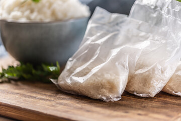 Raw rice in plastic bags on wooden background and cooked rice in bowl