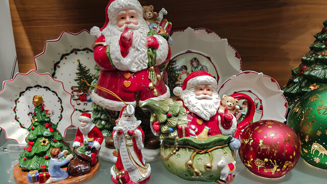 Handmade Christmas and New Year decorations with the image of Santa Claus. Christmas shopping concept. Hand choosing and buying xmas toys and crockery from shelf in store with Santa Clauses in hat.