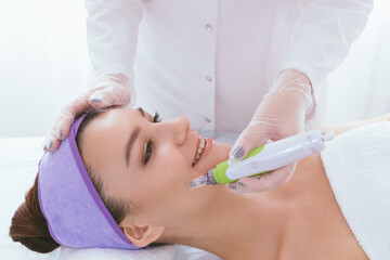 Naklejka premium Fractional mesotherapy.A young beautiful woman in the cosmetologist’s office receives fractional mesotherapy for her face. Facial skin rejuvenation. Acne treatment. Hardware cosmetology. Beautician.