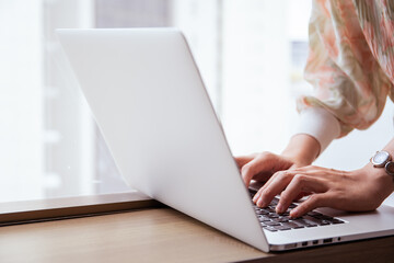 Fototapeta premium Happy Asian young woman making a video conference on laptop computer while living in the living room.