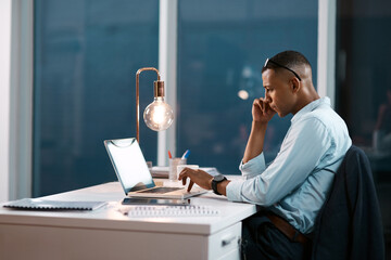 Handling business his own way. Shot of a handsome young businessman working on his laptop during a...