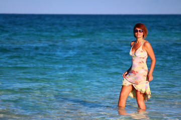 A happy young woman walks on the turquoise water of the sea. Soft focus, a place to copy.