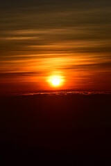 The sun set behind thick forests followed by mountains.