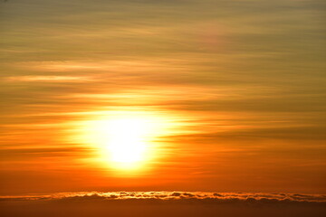 The sun set behind thick forests followed by mountains.