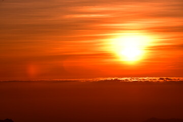 The sun set behind thick forests followed by mountains.