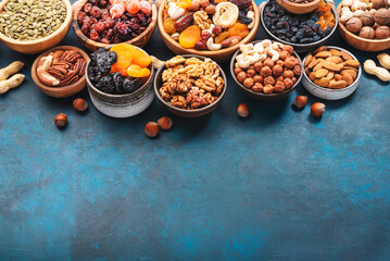 Nuts and dried fruits in assortment. Dry apricots, figs, raisins, walnuts, almonds and other. Blue table background, top view, copy space