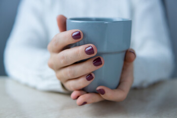 Hands of a young woman holding a cup