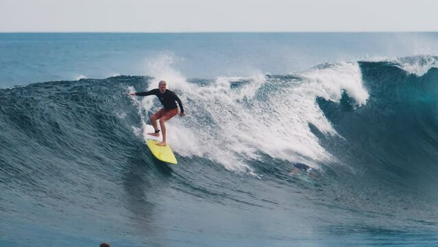 Surfing tough fall. Surfer rides big wave in Maldives during sunset and falls